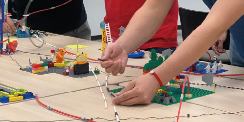 Participantes trazando conexiones entre modelos construidos con LEGO Serious Play durante un taller de estrategia y alineación organizacional