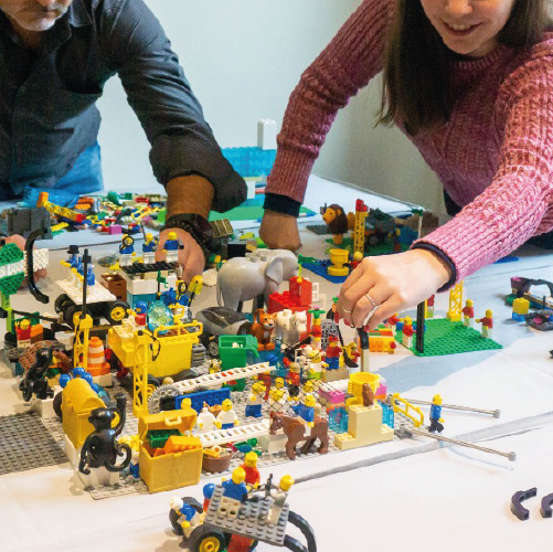 Dinámica con LEGO Serious Play para representar procesos organizacionales y roles, usando figuras de animales, obreros y estructuras en equipo